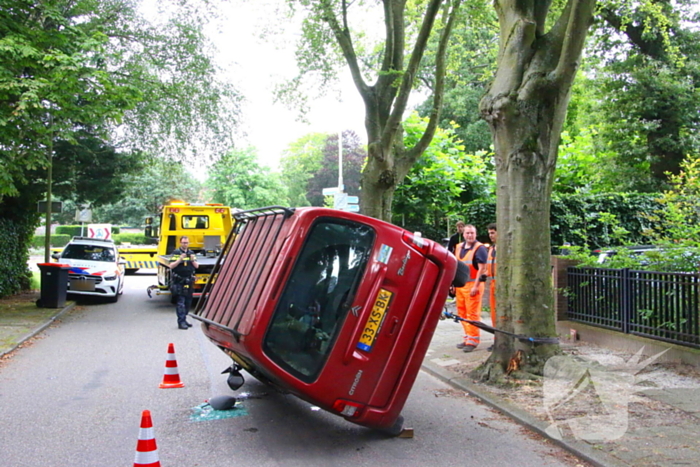 Auto belandt op zijkant na botsing tegen boom