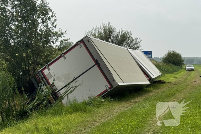 Vrachtwagen belandt in sloot naast snelweg, chauffeur ongedeerd