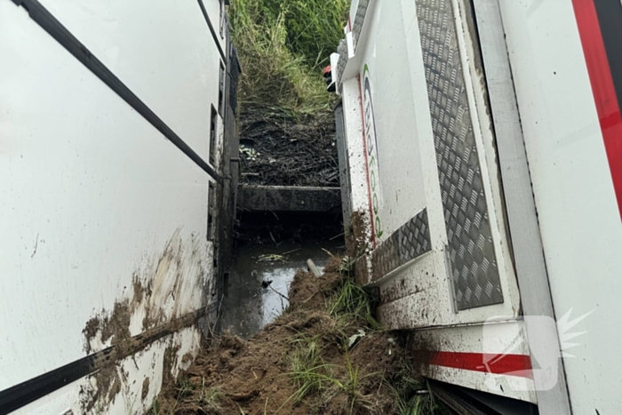 Vrachtwagen belandt in sloot naast snelweg, chauffeur ongedeerd