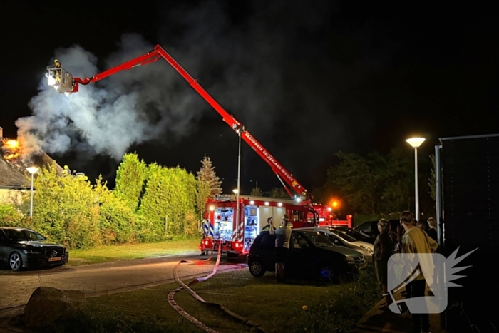 Vlammen slaan uit rietendak van woning