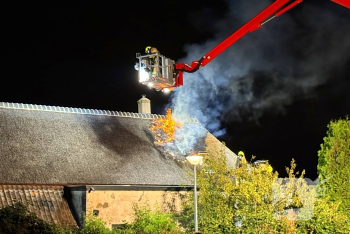 Vlammen slaan uit rietendak van woning