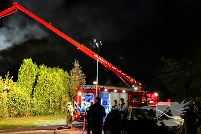 Vlammen slaan uit rietendak van woning