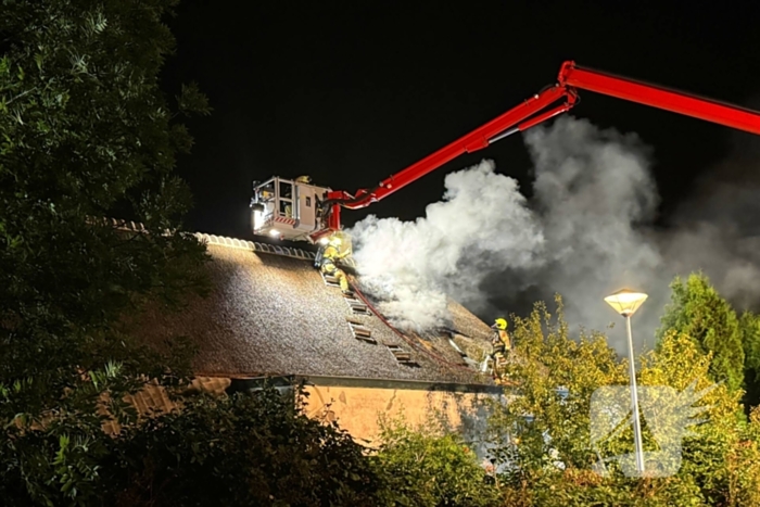 Vlammen slaan uit rietendak van woning