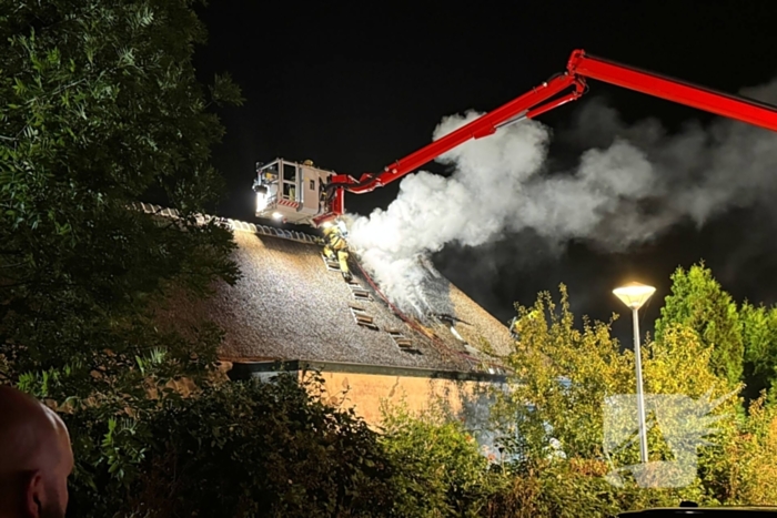 Vlammen slaan uit rietendak van woning