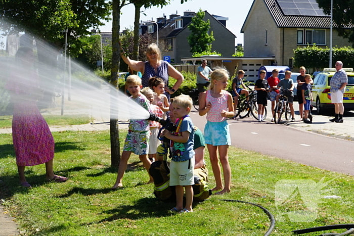 Kinderen blussen met brandweer brandende coniferenhaag