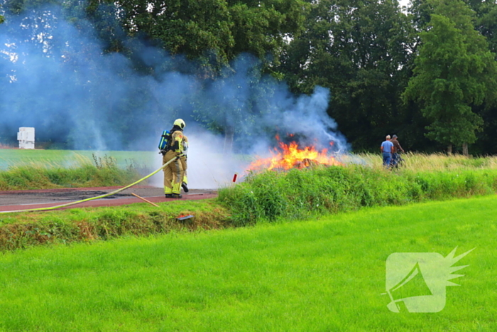 Brandweer blust brandend stro op aanhanger