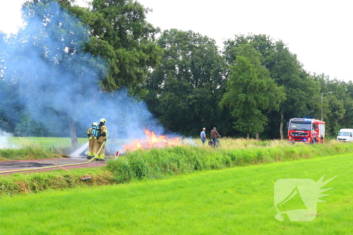 Brandweer blust brandend stro op aanhanger