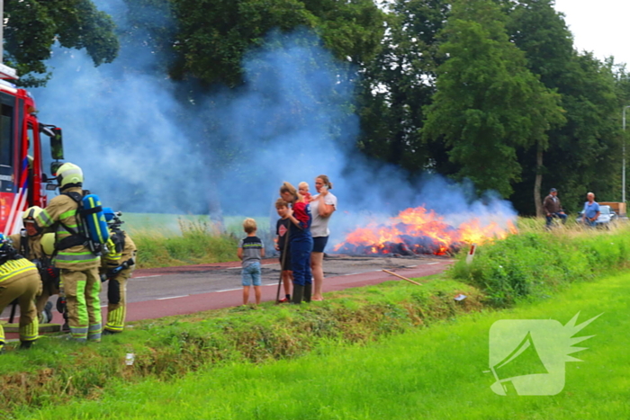 Brandweer blust brandend stro op aanhanger