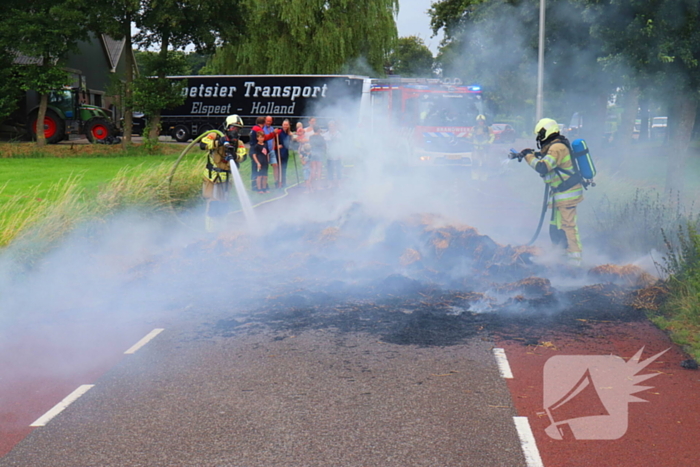 Brandweer blust brandend stro op aanhanger