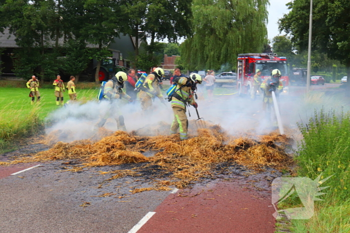 Brandweer blust brandend stro op aanhanger