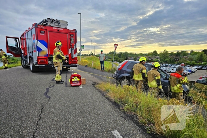 Brandweer trekt auto terug de dijk op