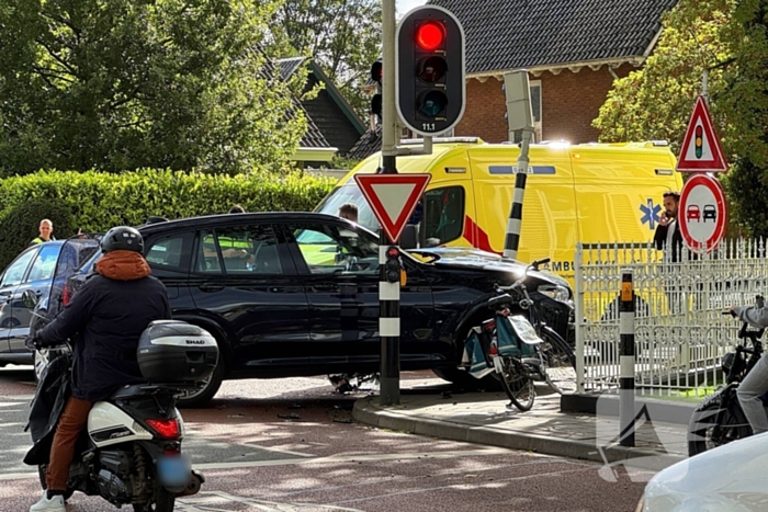 Twee voertuigen botsen op elkaar waarna een op een verkeerslicht klapt