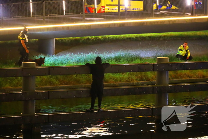 Persoon klimt op palen onder brug en word gebeten door politiehond