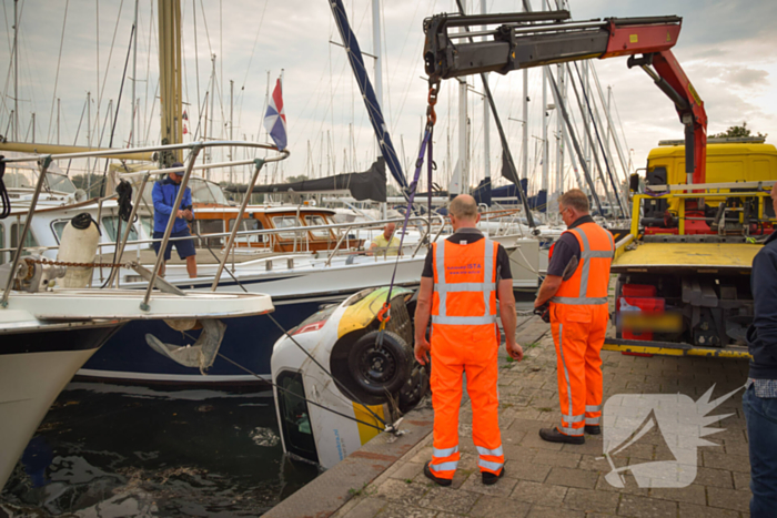 Auto rolt jachthaven in en gaat kopje onder