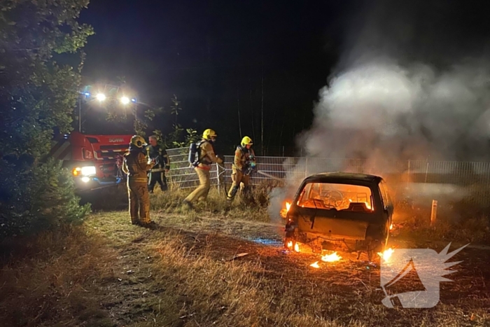 Brandweer blust brandende auto in bosgebied