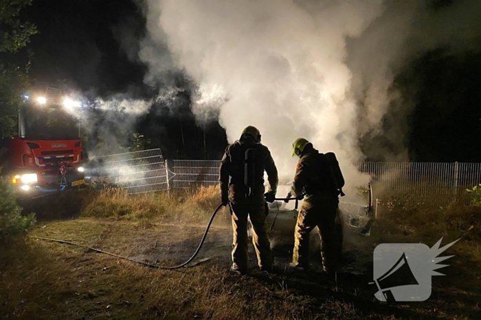 Brandweer blust brandende auto in bosgebied