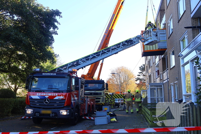 Persoon door hijskraan uit flatwoning getakeld