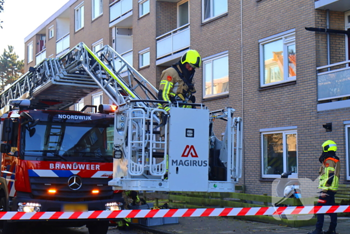 Persoon door hijskraan uit flatwoning getakeld