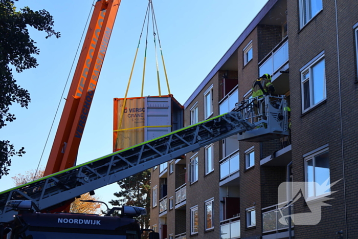 Persoon door hijskraan uit flatwoning getakeld