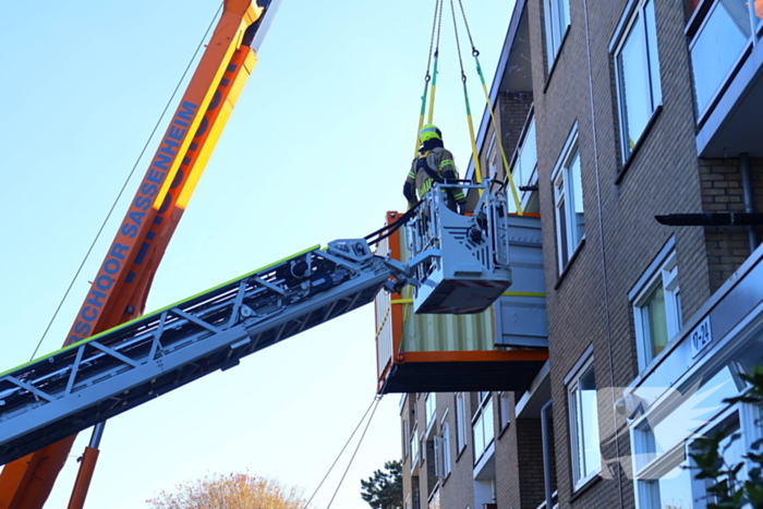 Persoon door hijskraan uit flatwoning getakeld