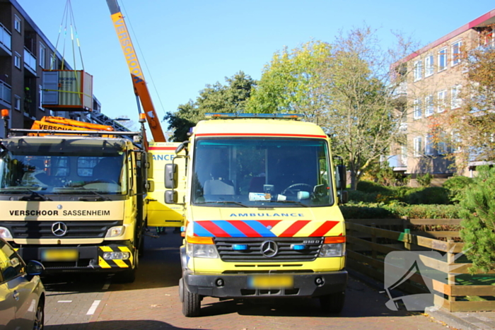 Persoon door hijskraan uit flatwoning getakeld