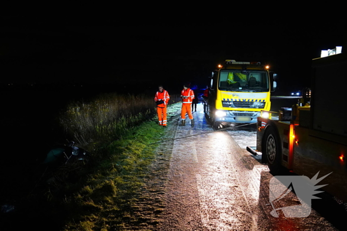 Twee auto's te water in bocht op gladde dijk