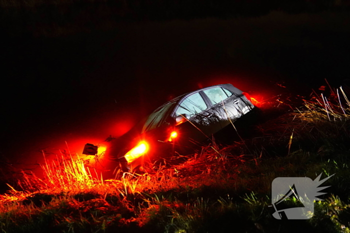 Twee auto's te water in bocht op gladde dijk