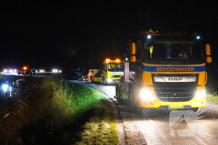 Twee auto's te water in bocht op gladde dijk