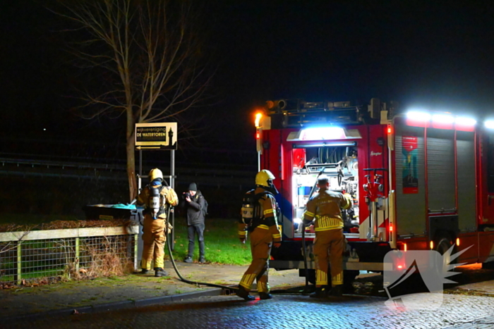 Brandweer blust brand in vuilcontainer