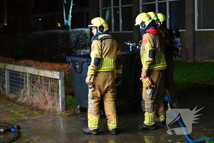 Brandweer blust brand in vuilcontainer