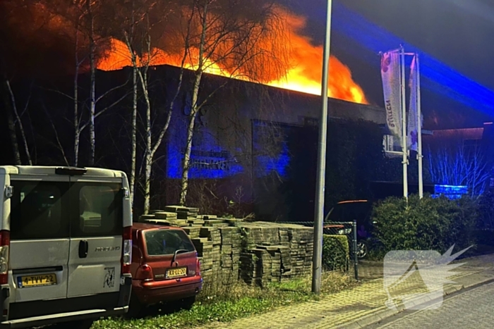 Vlammen slaan uit dak van gebouw