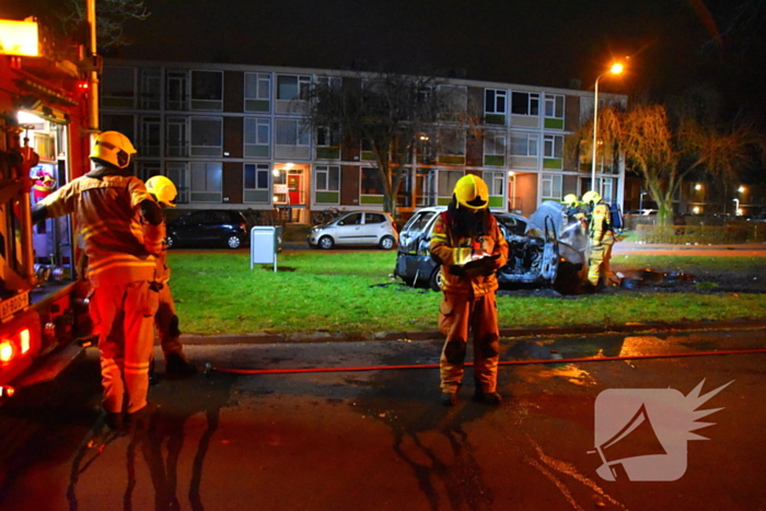 Auto in brand gestoken op grasveld