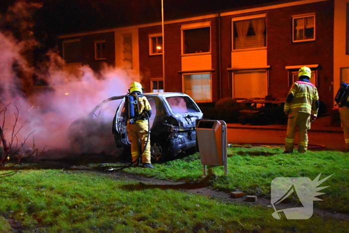 Auto in brand gestoken op grasveld